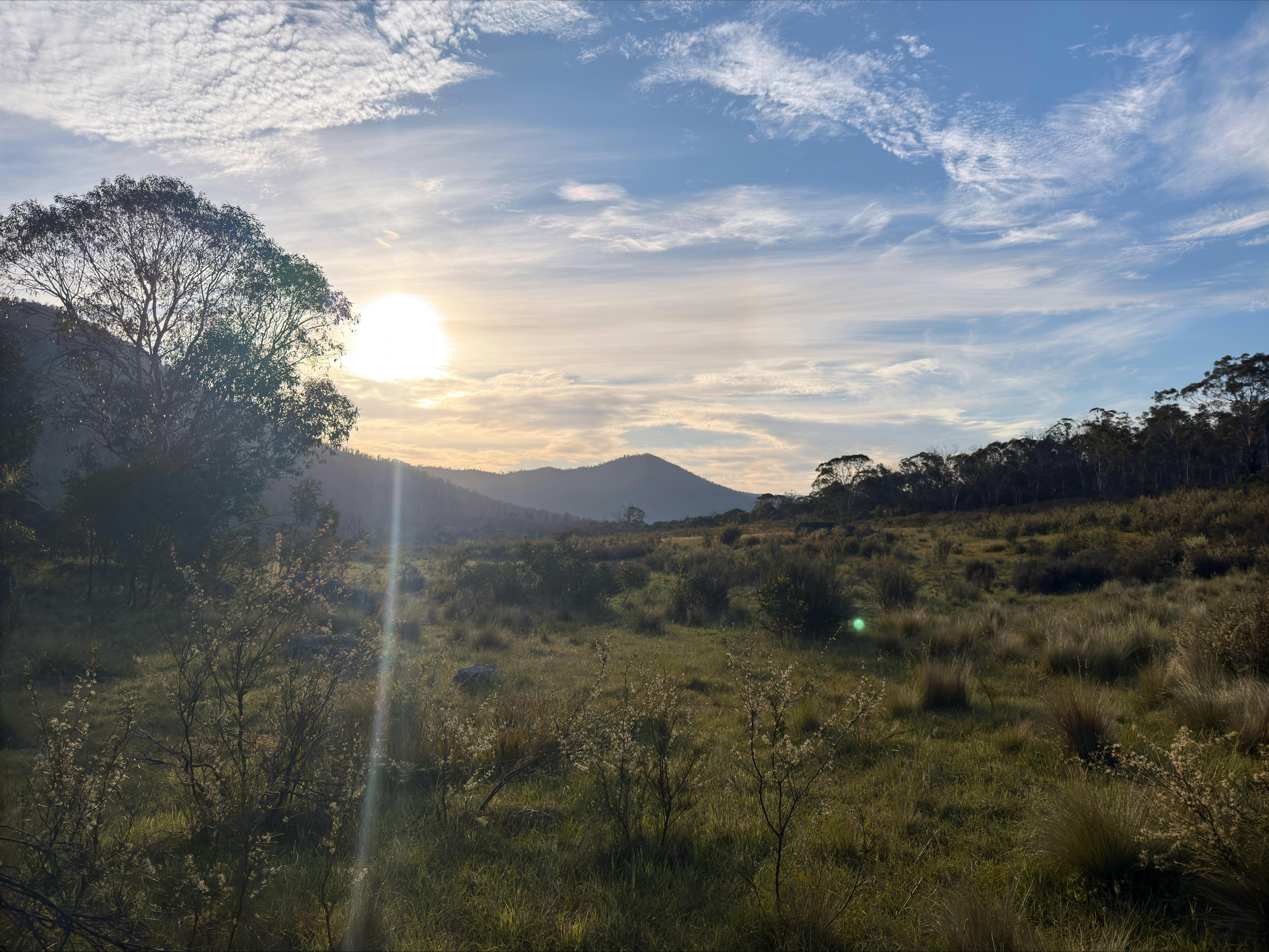 A mountain with the sun setting behind it.