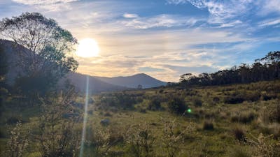 A mountain with the sun setting behind it.