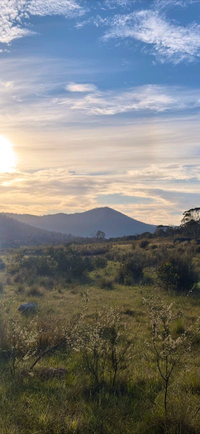 A mountain with the sun setting behind it.