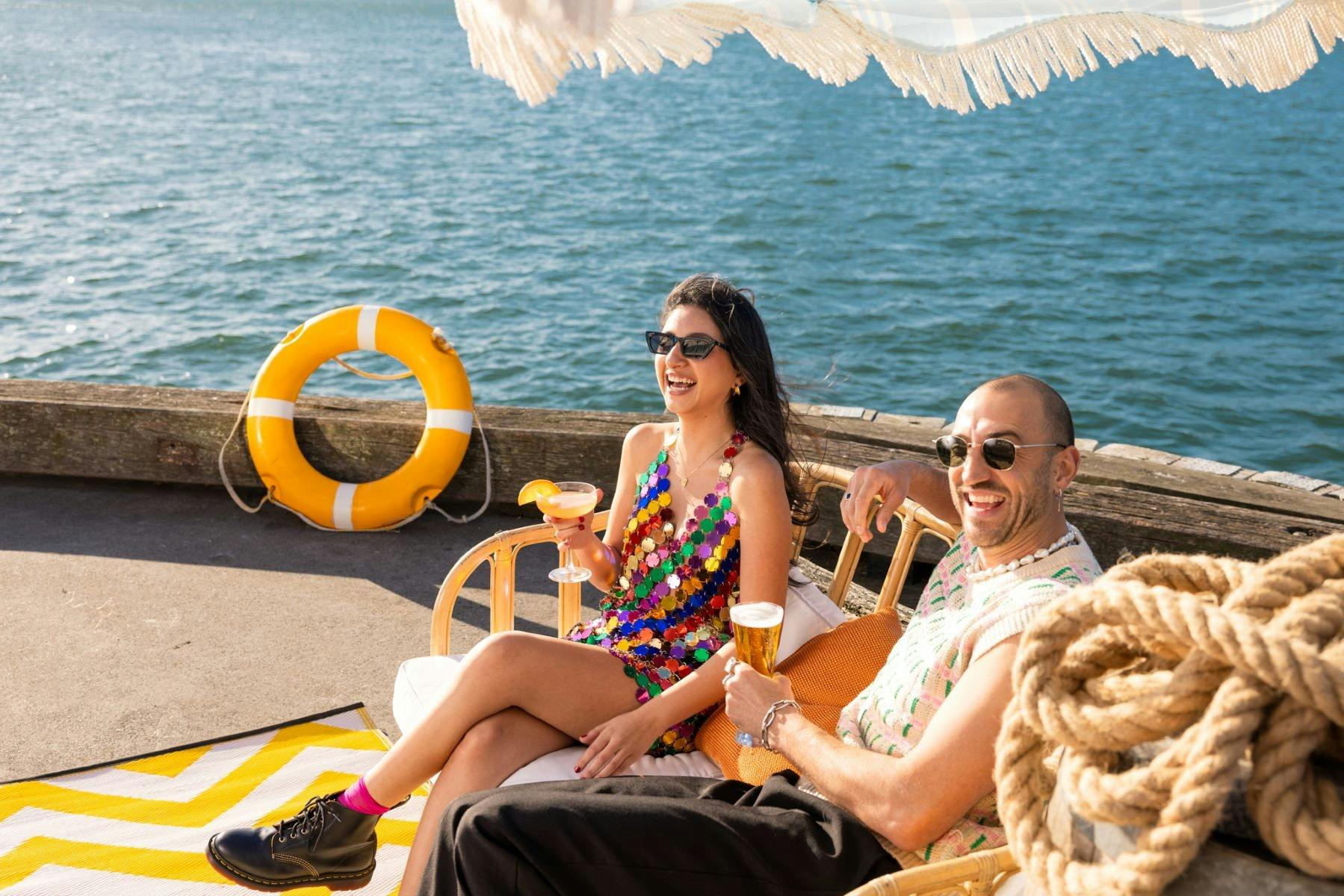 Two people seated on chairs, enjoying drinks together in a relaxed setting.