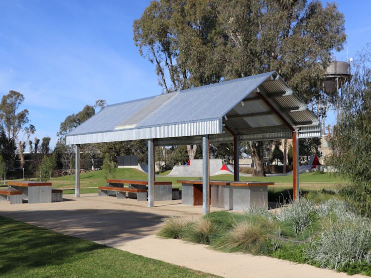 Large barbeque shelter at Apex Park with skate park in the background