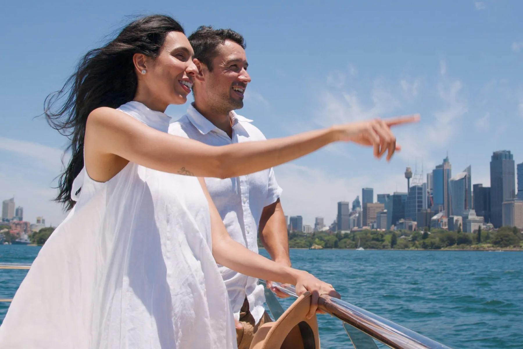 man and woman on sightseeing cruise pointing at a landmark