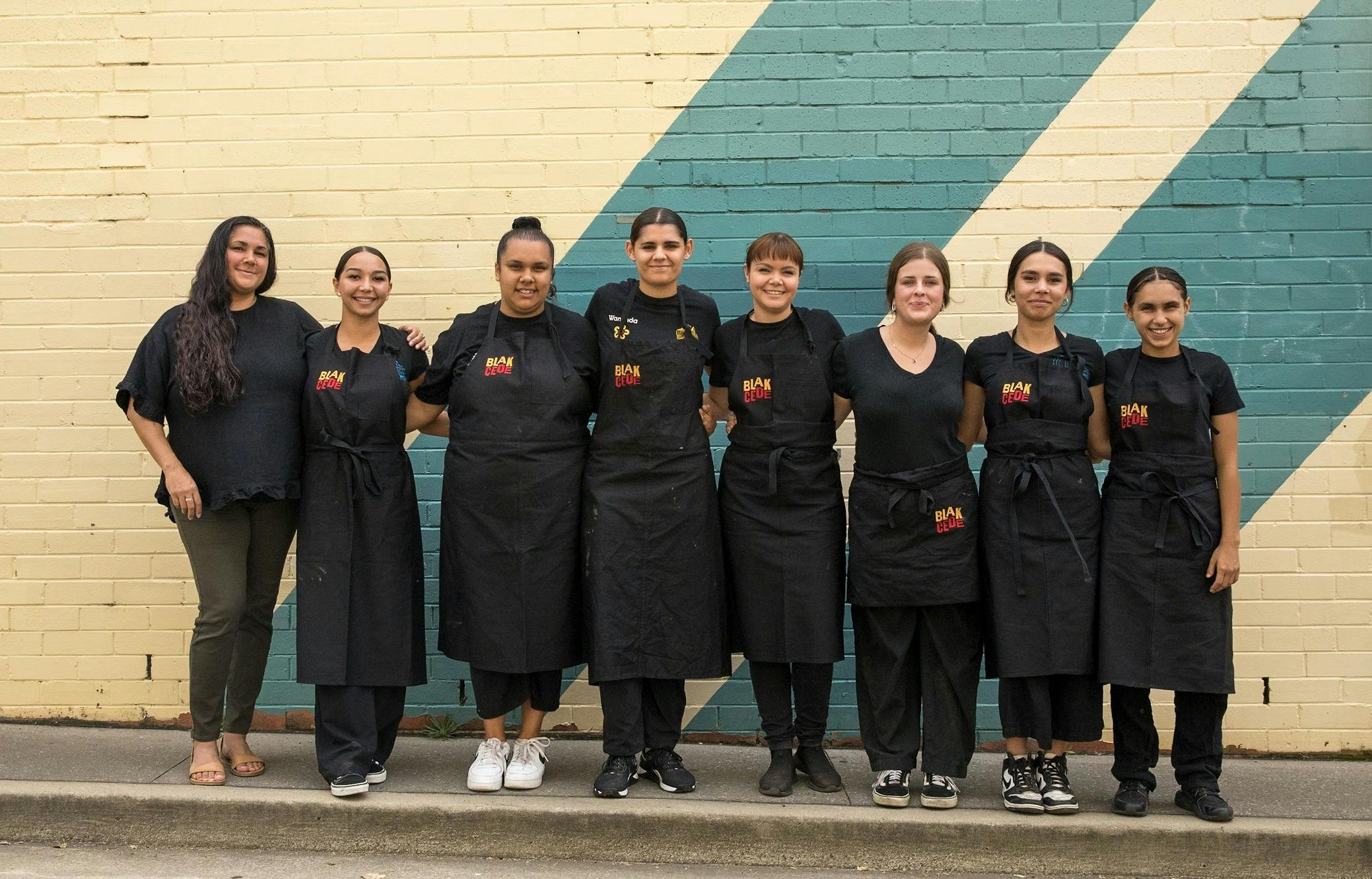 Eight Blak Cede staff standing in line smiling for photo