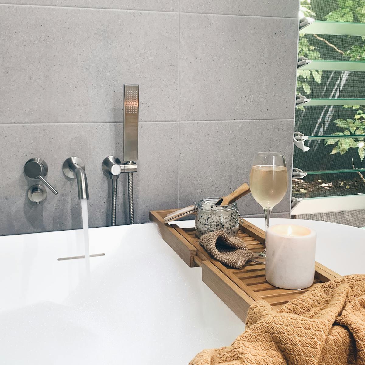 Soaking tub filled with water and bubbles with wine glass