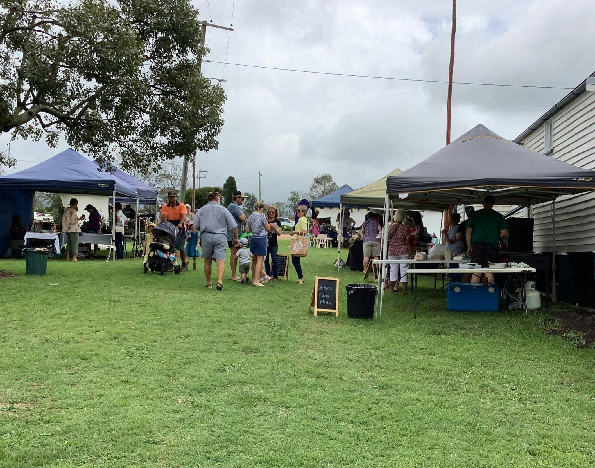 Photo of grassy area with pop up gazebos and people milling about.