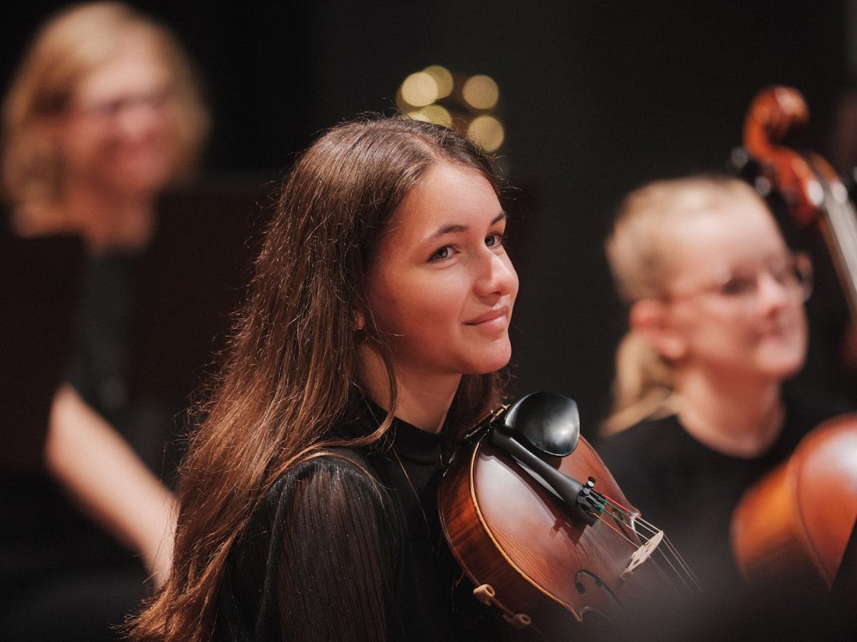 Young girl plays violin in an orchestra