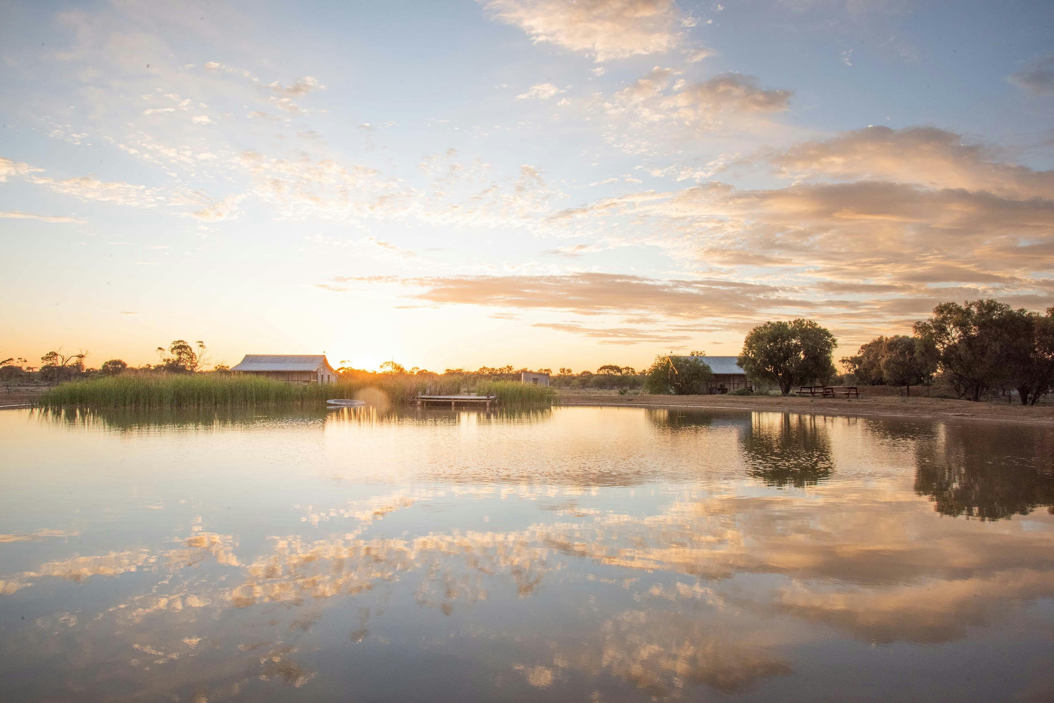 A sunset view of cottages next to a body of water