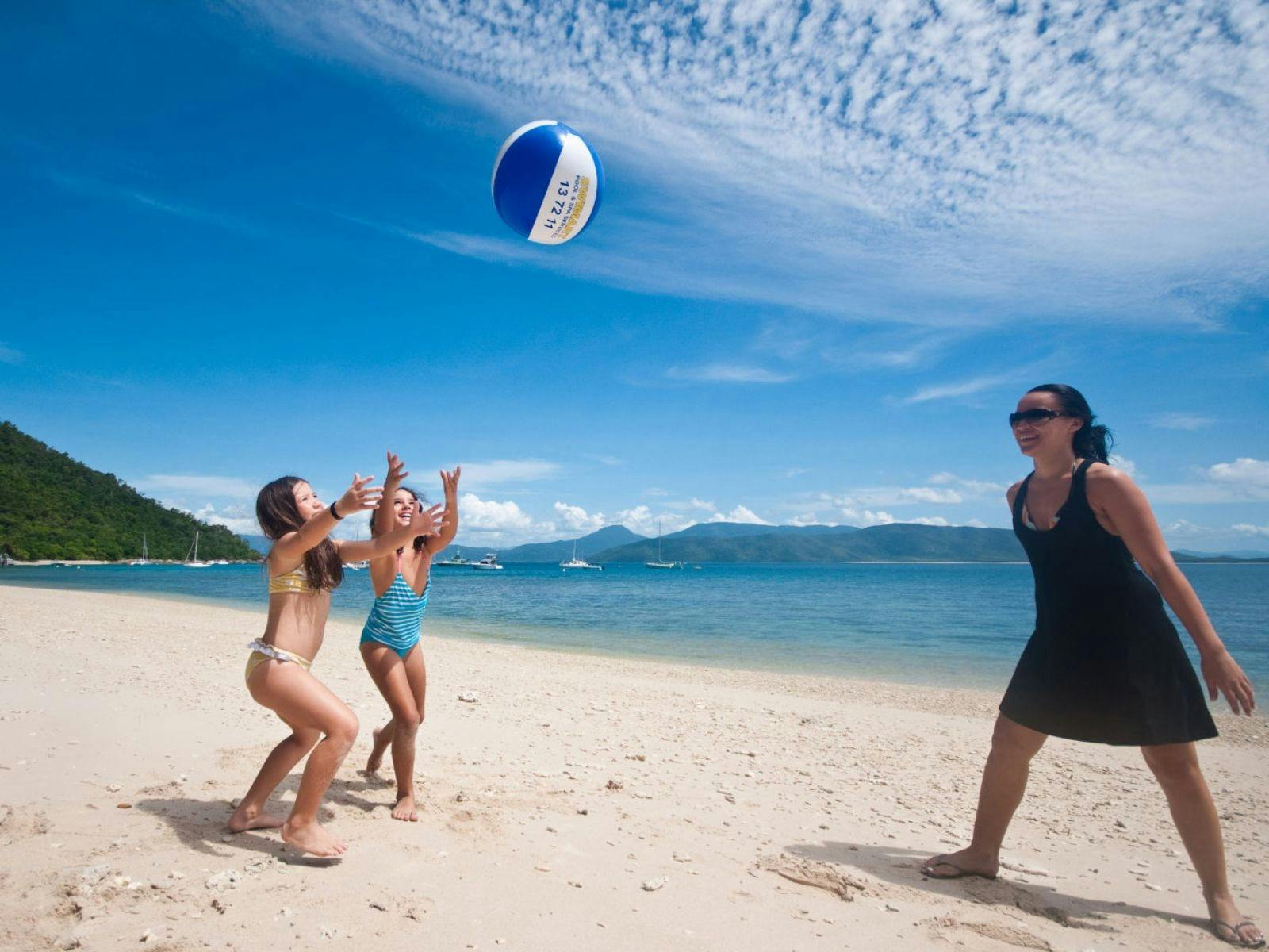Family playing a ball game together on the sandy shores of Fitzroy Island, Great Barrier Reef