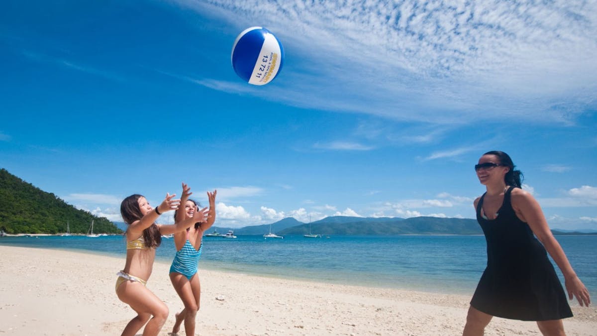 Family playing a ball game together on the sandy shores of Fitzroy Island, Great Barrier Reef