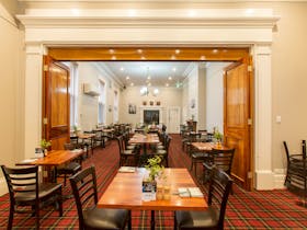 An interior view of a bistro dining area with neatly arranged wooden tables and chairs, red and blac