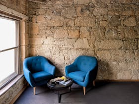 Chairs and a coffee table by the window, warm sandstone walls