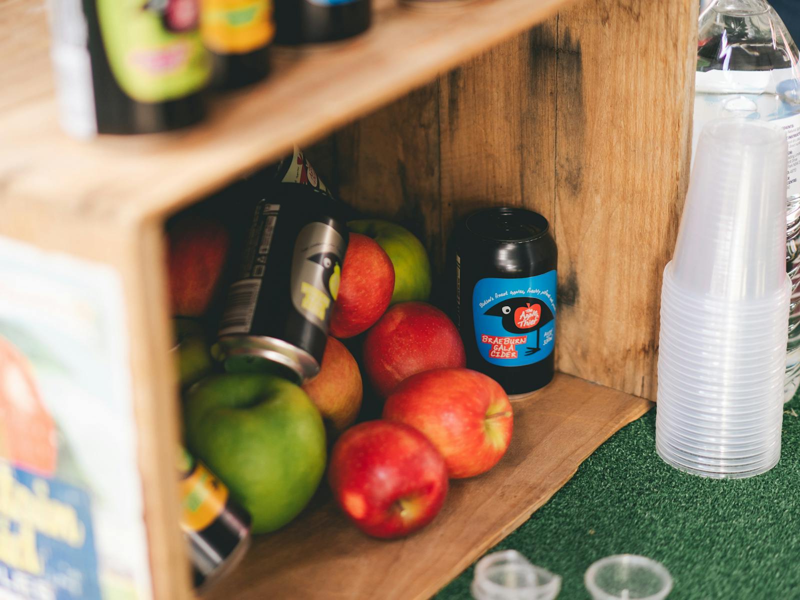 Apples and cider on display in a wooden box.