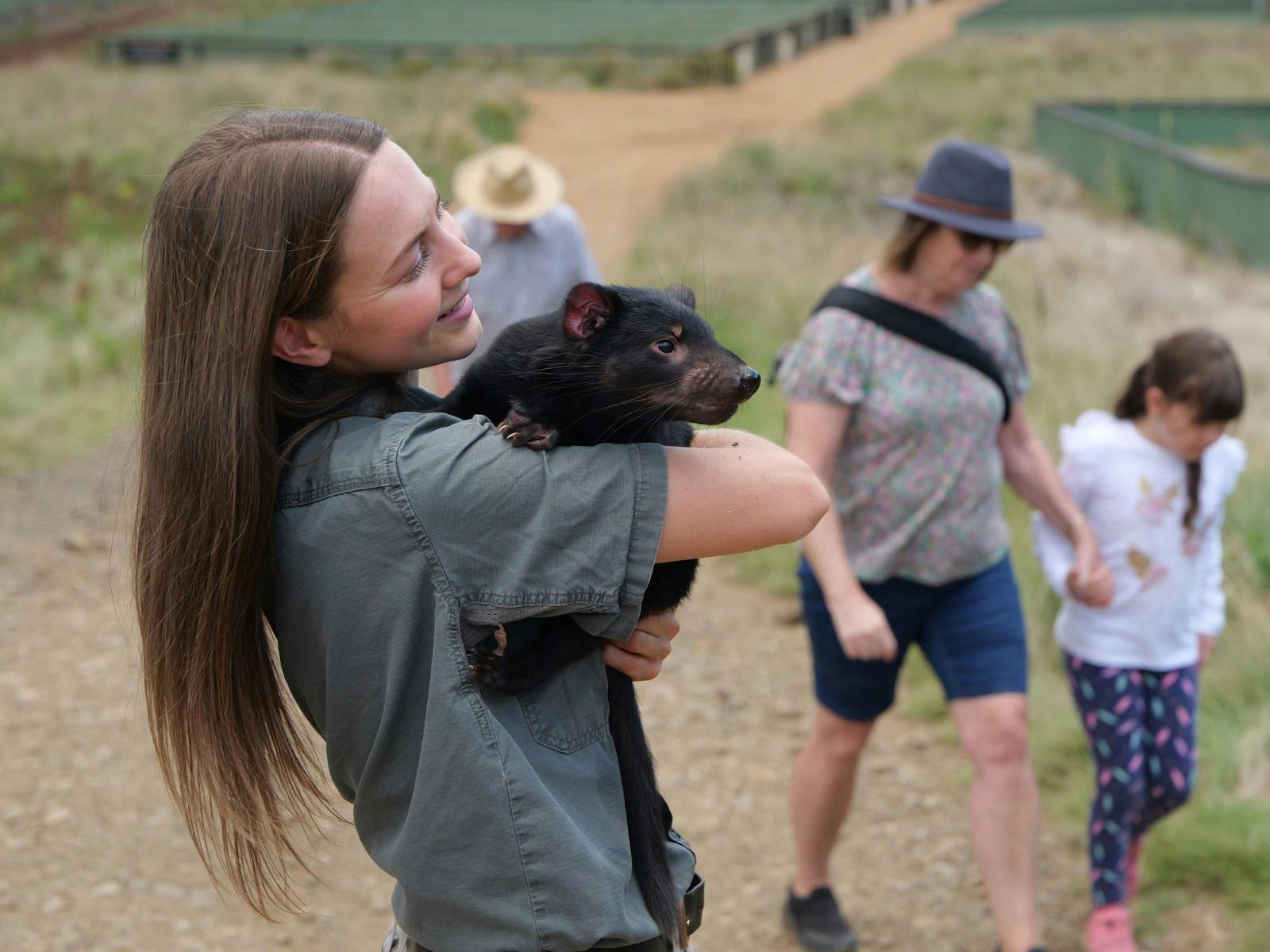 Ranger Laura Chapman, holding a Tasmanian Devil joey called Newy.