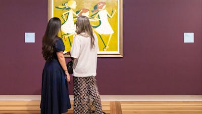 Two people in formal clothing view a portrait hung on a Gallery wall depicting three young girls.