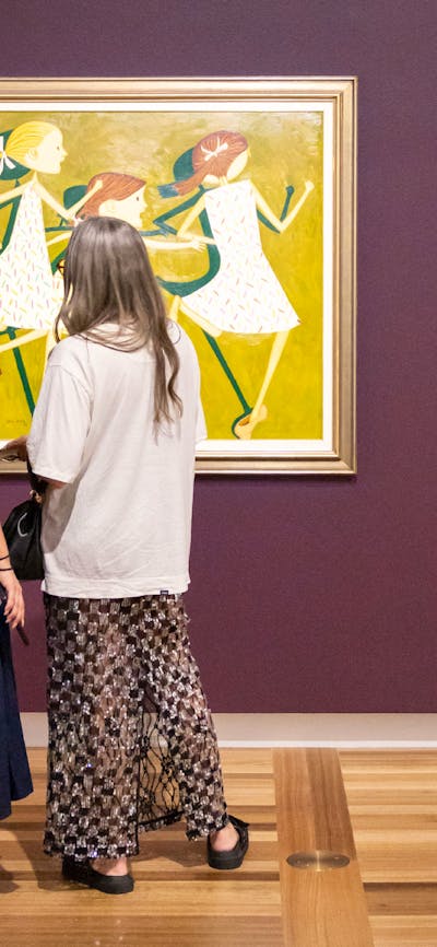 Two people in formal clothing view a portrait hung on a Gallery wall depicting three young girls.