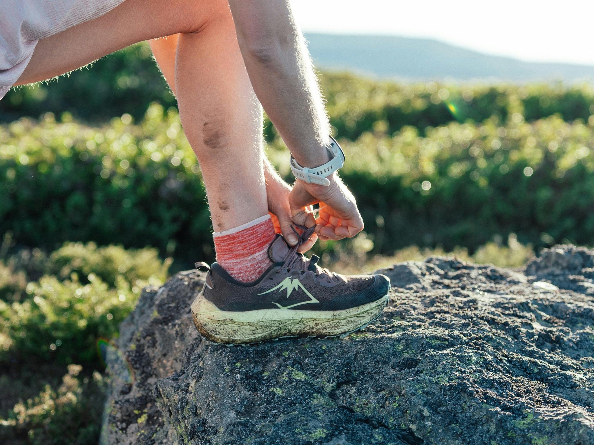 Sole person tying shoelaces with muddy arms, legs and shoes