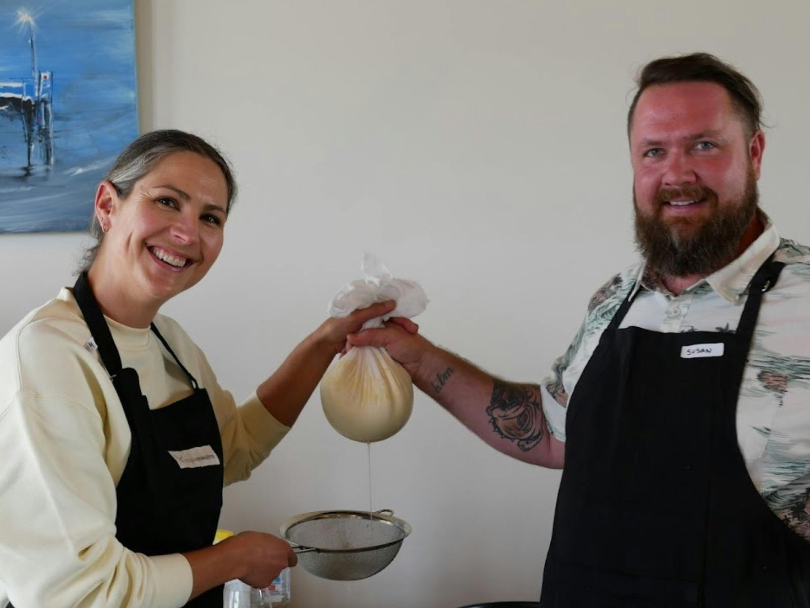 A couple holding up the cheese they are meking in a cheese class