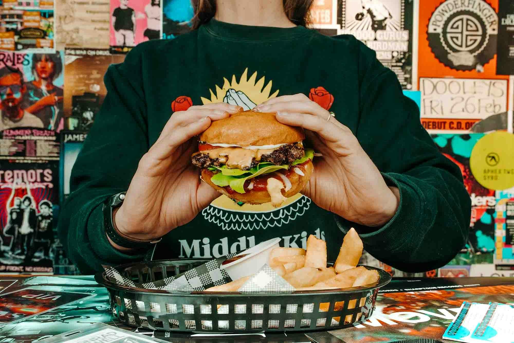 Two hands holding up a Triffid Burger.