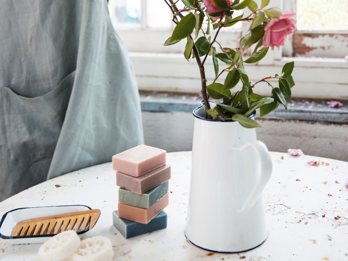 Image of 6 Washpool handmade soap bars, sitting on table with vase and flowers, next to soap tray