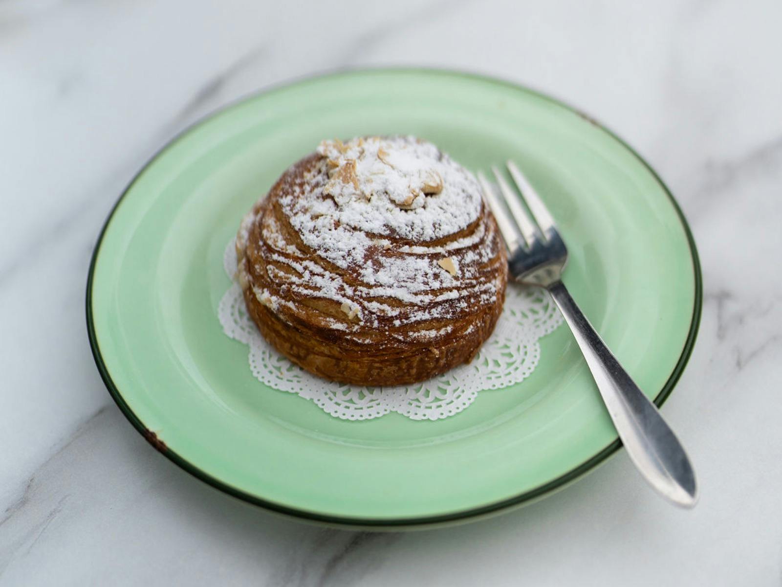 an almond croissant on a green plate