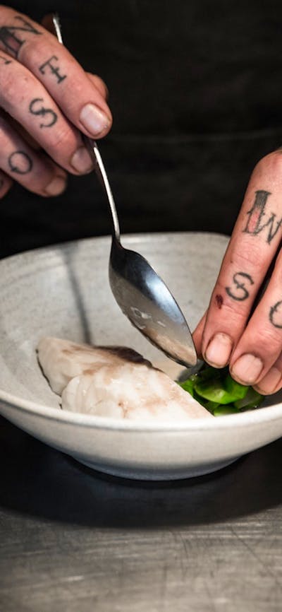Head Chef Malcolm Hanslow plating a dish of steamed fish and greens.