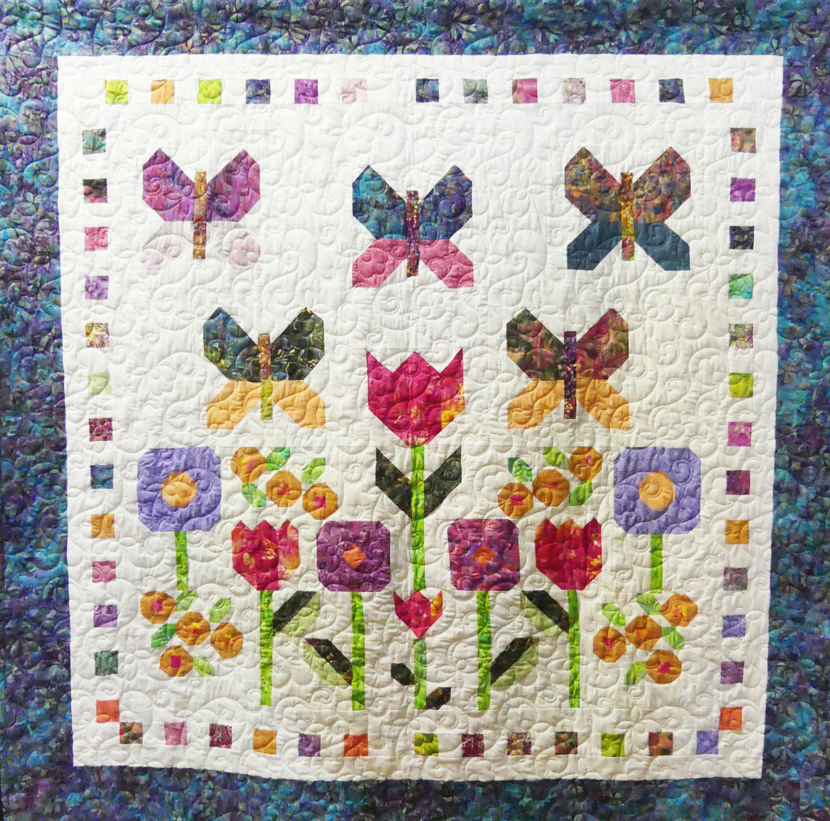 Appliqued butterflies and flowers on a white background with a blue border.