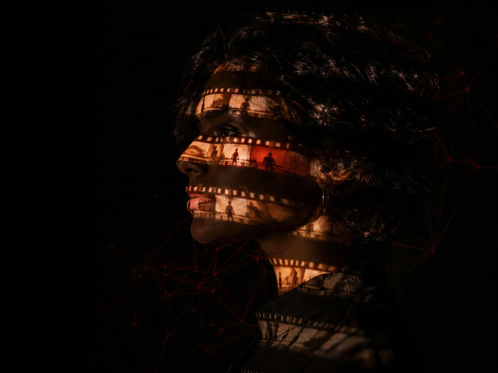 woman in darkness with 35mm strips of film projected on face