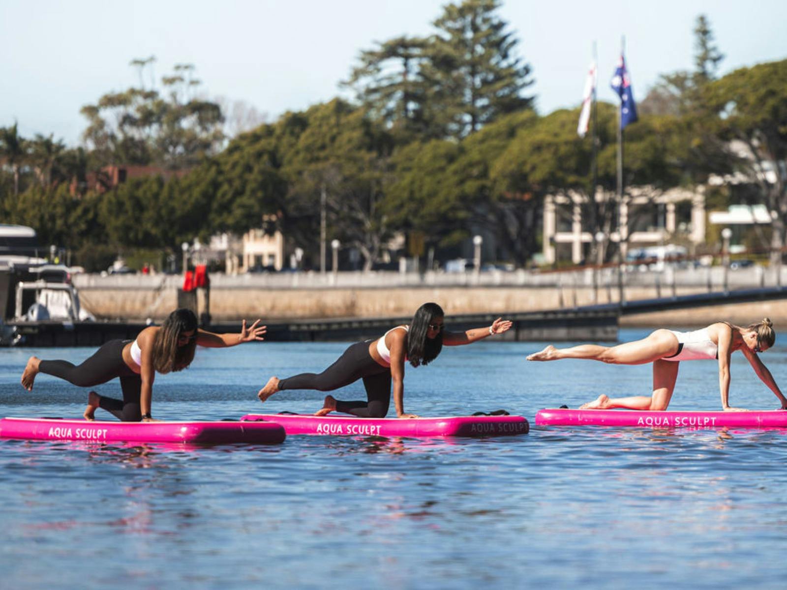 Photo of 3 women doing Pilates on top of a floating board used as an exercise platform.
