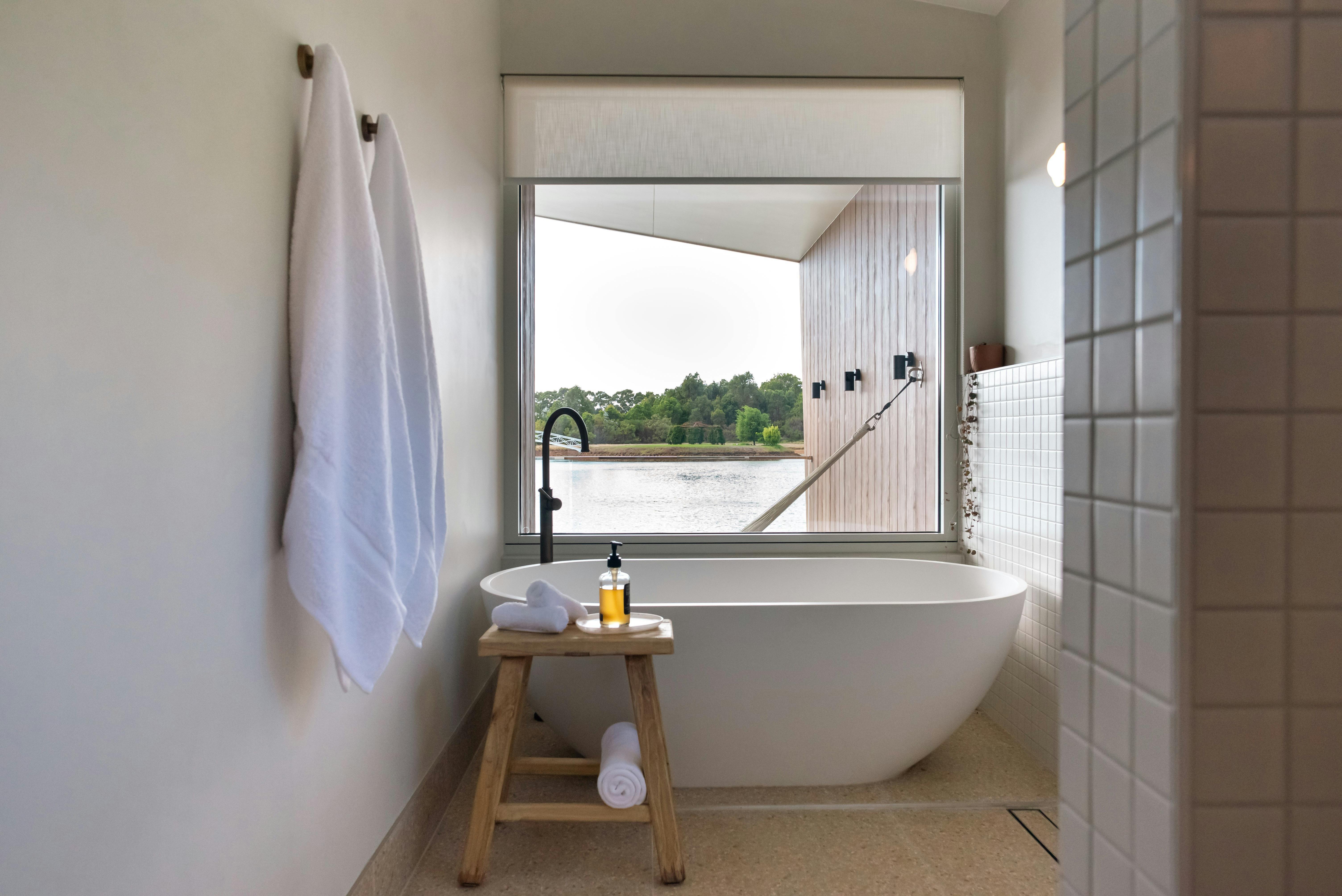 Freestanding bath at Edge Luxury Villas with large window overlooking the lake and forest.