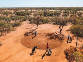 Drone view of four golf players on the red sand greens of Quilpie Golf Course