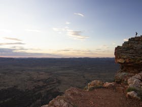 Man up on a rock escarpment looking over West Macdonnell Ranges