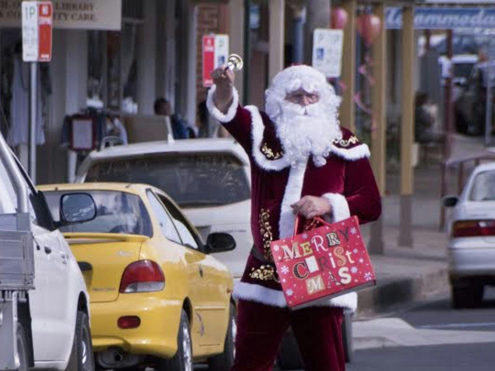 Santa Claus walks along street ringing bell