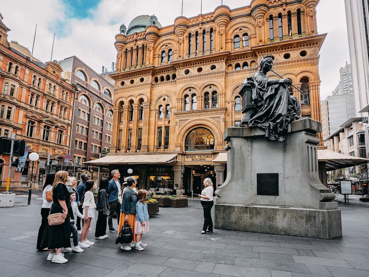 A tour group on the QVB History Tour looking at the Queen Victoria statue outside