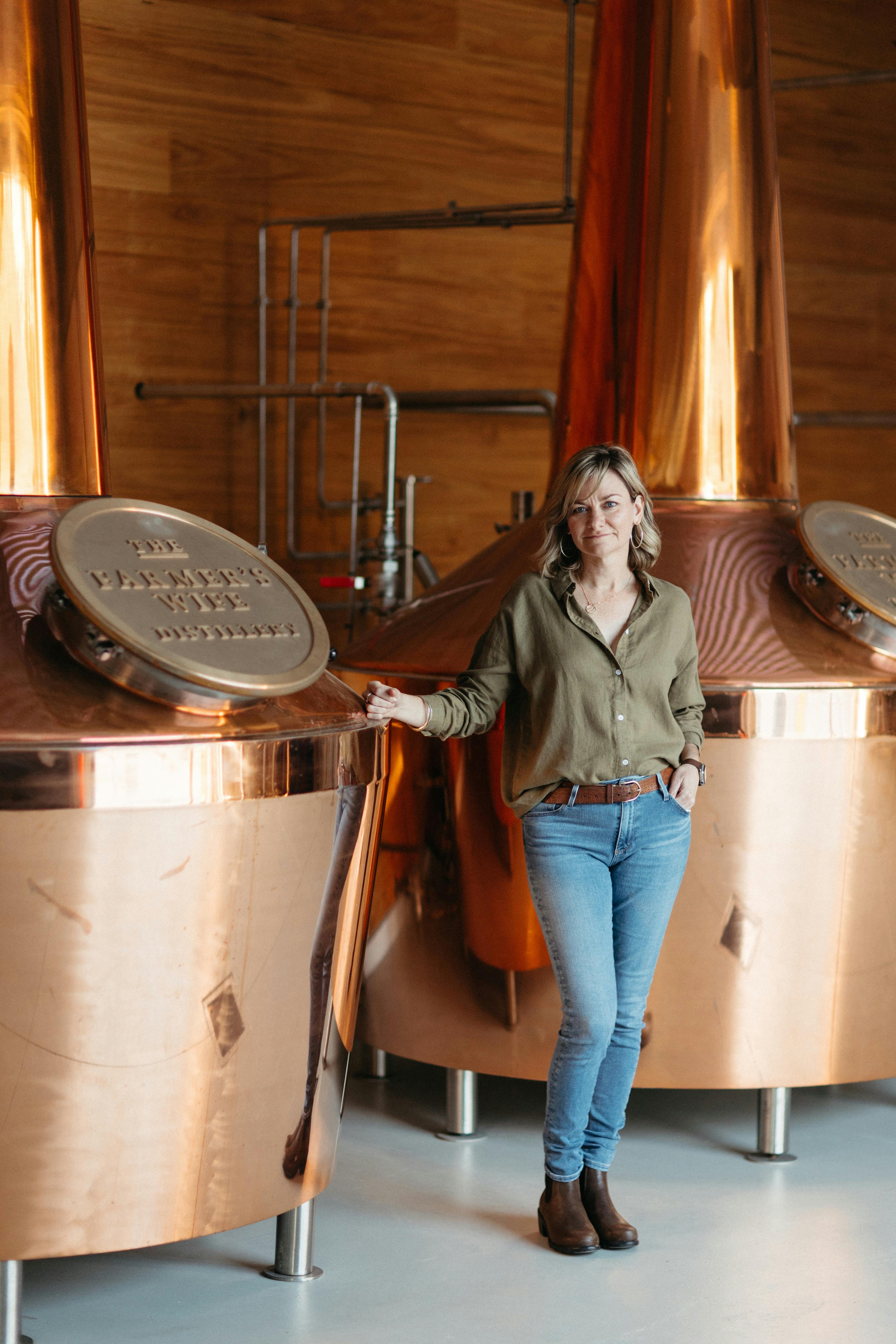 Owner & Distiller - Kylie Sepos Standing by two copper pot stills