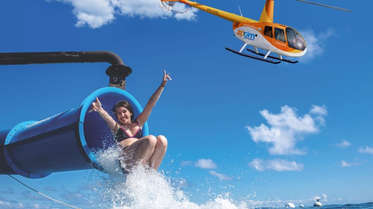 Girl sliding down the only waterslide on the Great Barrier Reef (Moore Reef), with a Zoom Helicopter