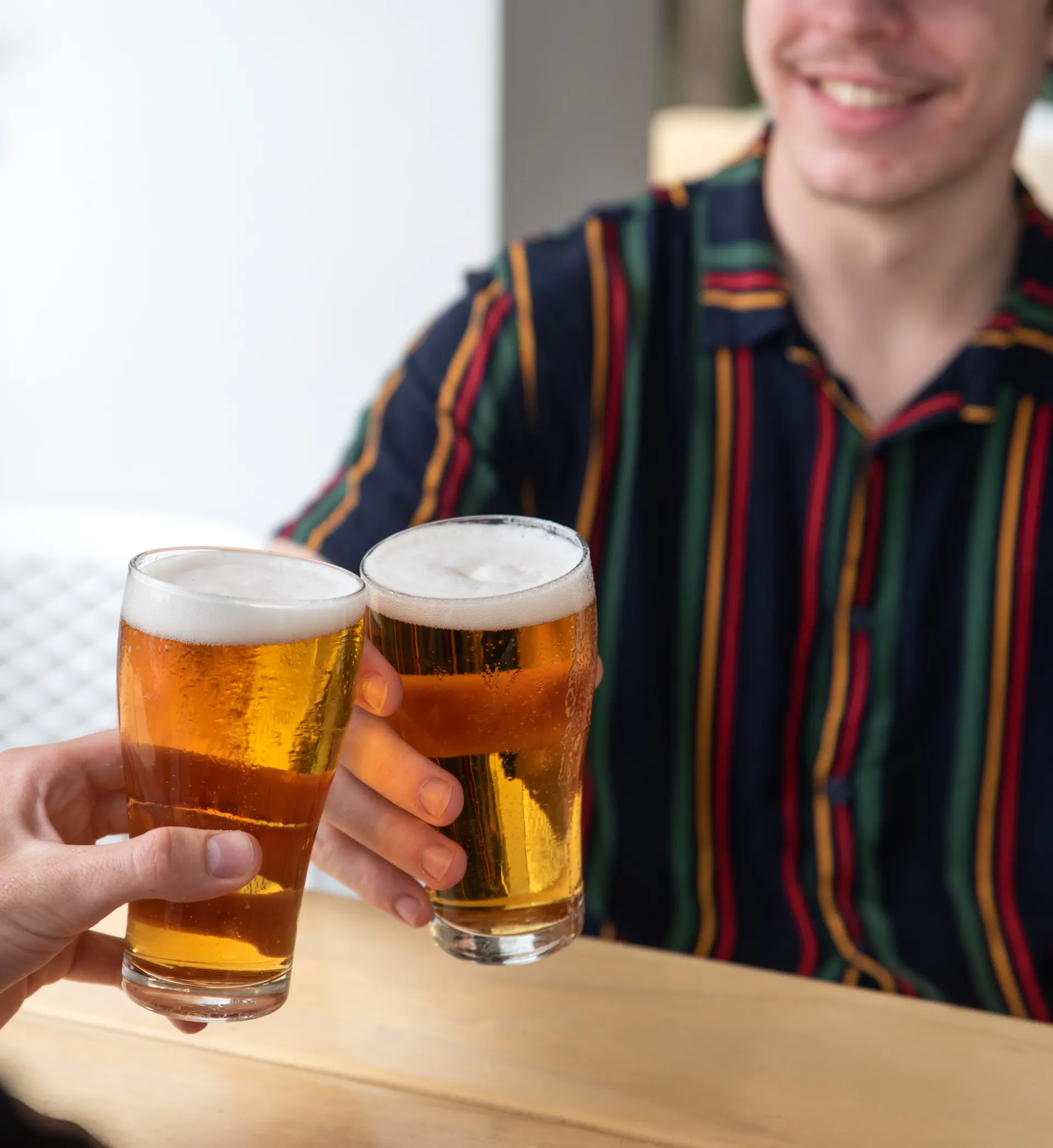 Two men cheersing a schooner glass of beer
