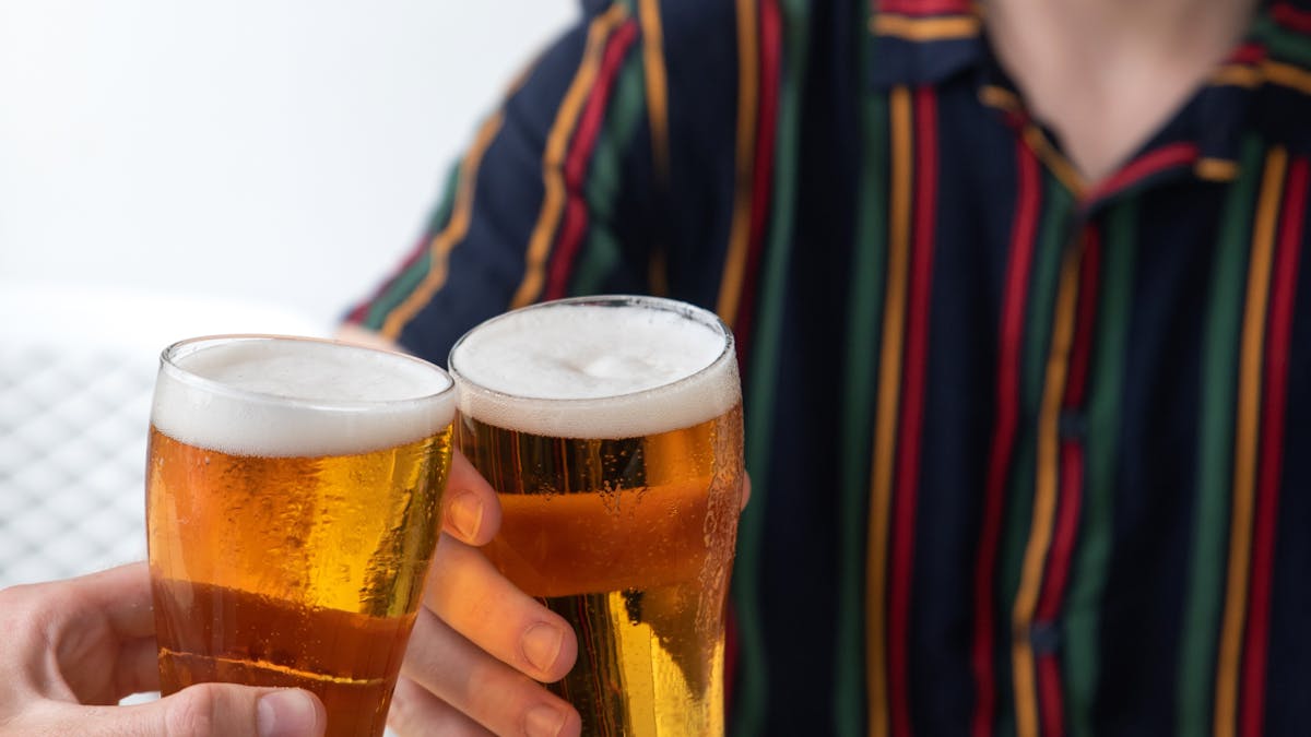 Two men cheersing a schooner glass of beer