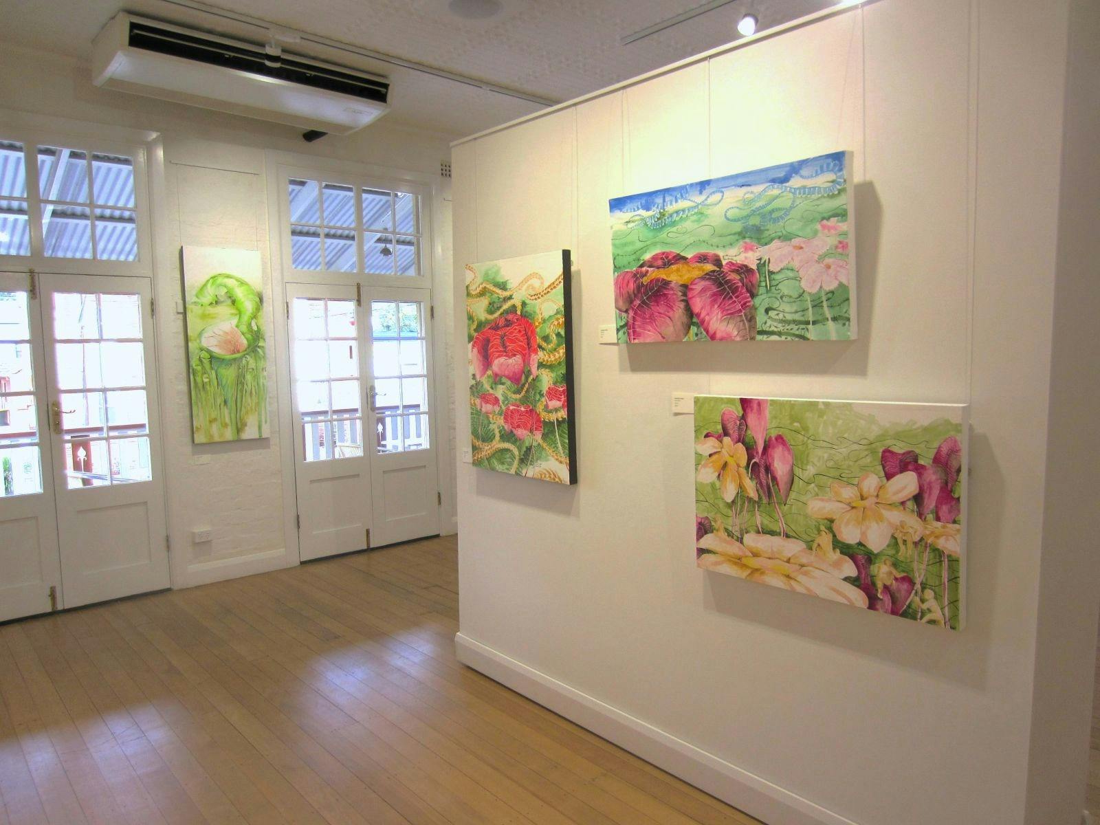Paintings on walls with lots of pinks and greens.