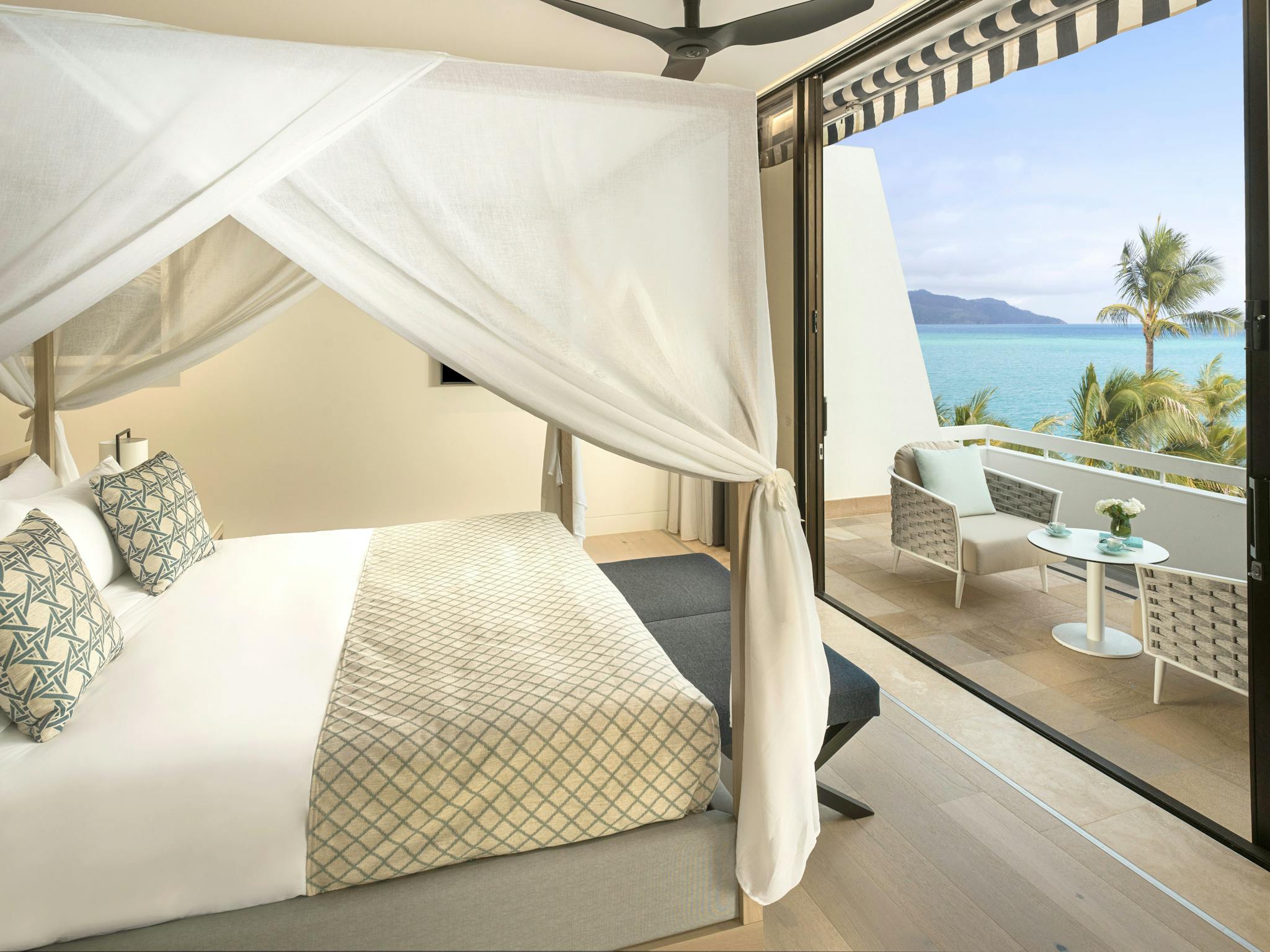 A cozy bedroom with a canopy bed, leading to a balcony with seating and breathtaking ocean views. A cozy bedroom with a canopy bed, leading to a balcony with seating and breathtaking ocean views.