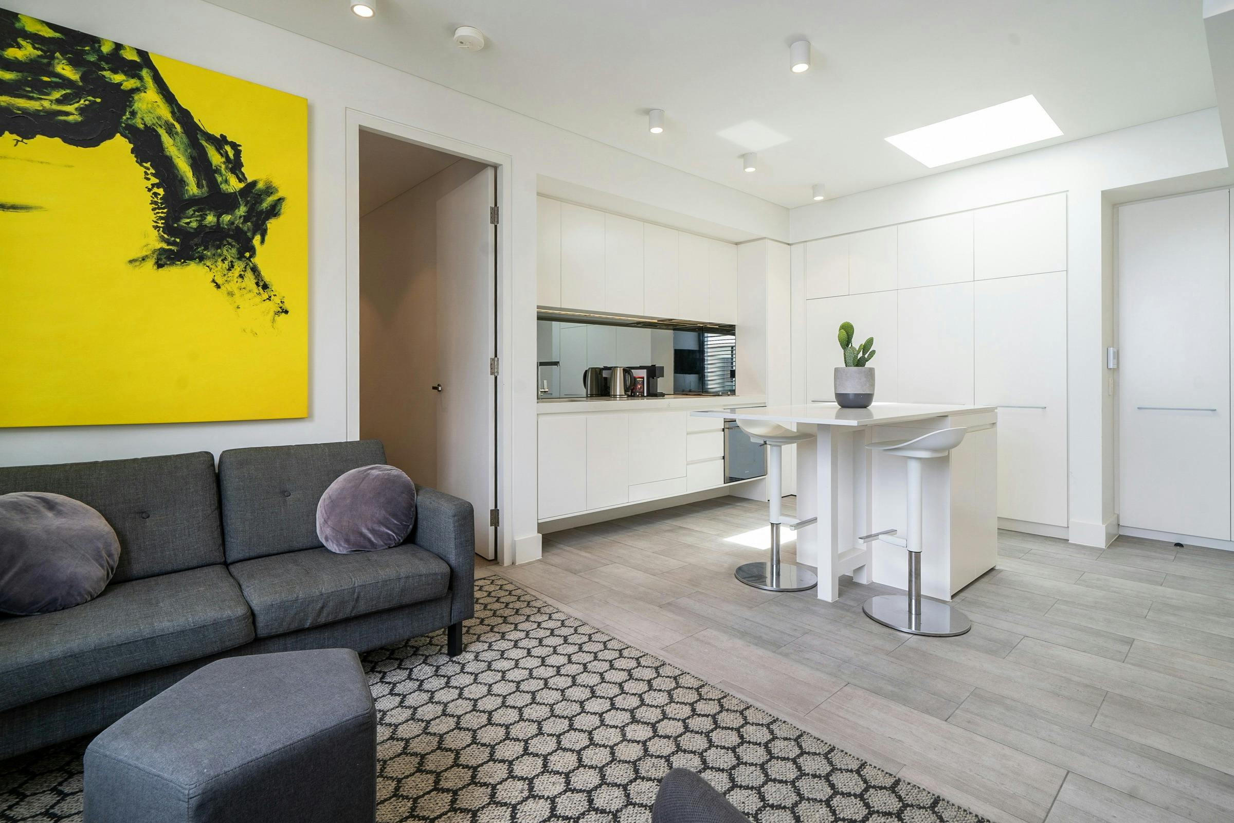 Contemporary living space with kitchen, lounge, and large windows offering natural light.