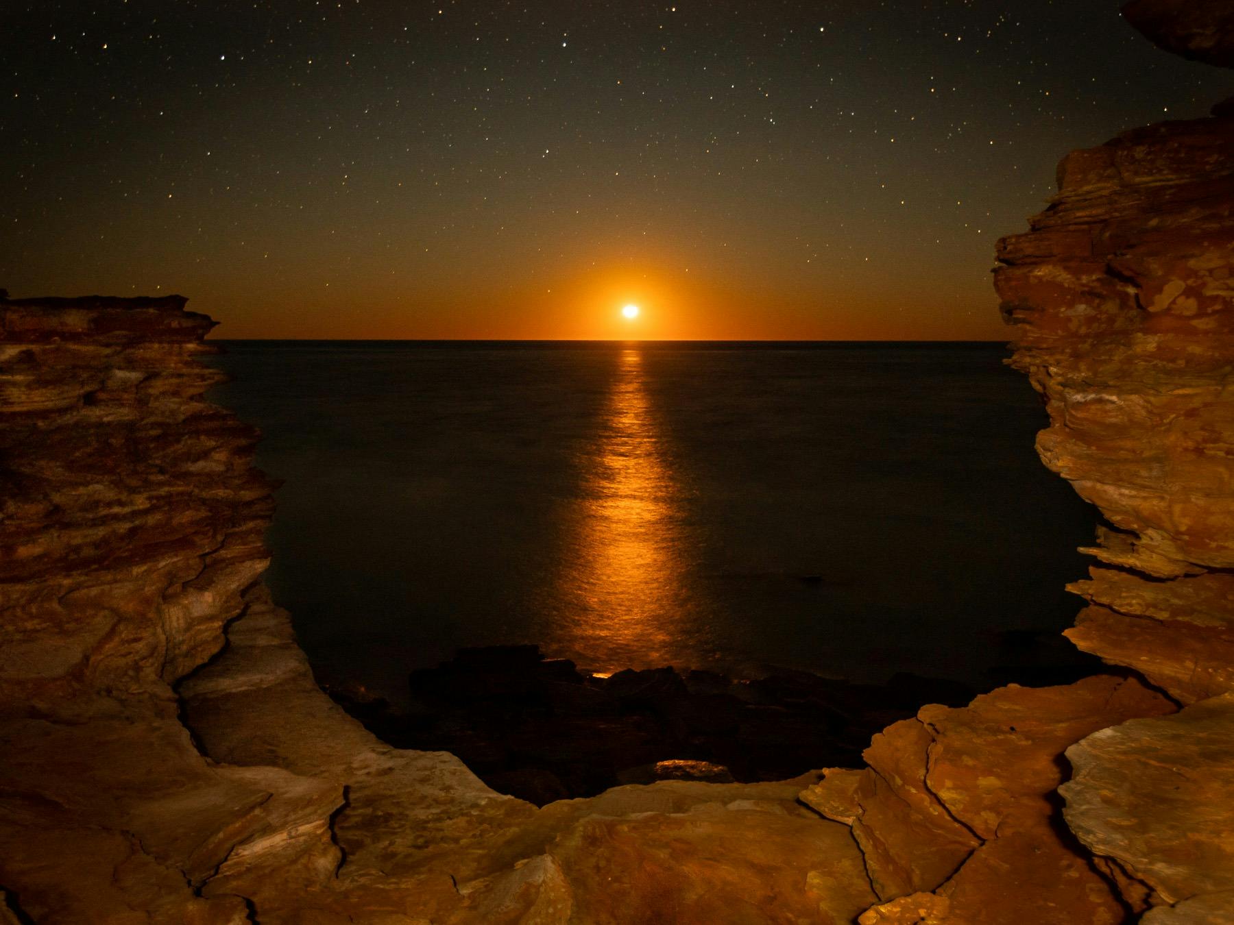 Starry night as the moon sets over the rocks in Broome