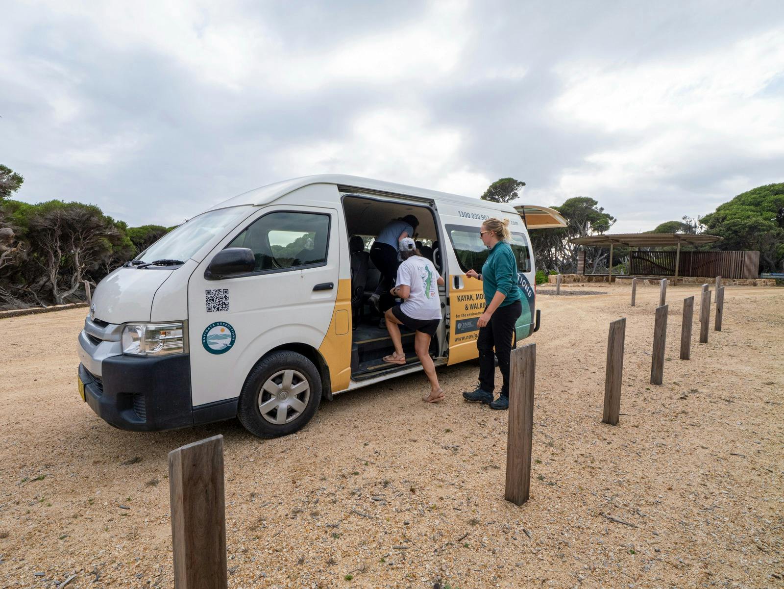 People getting into a mini-bus at Green Cape Lighthouse car park.