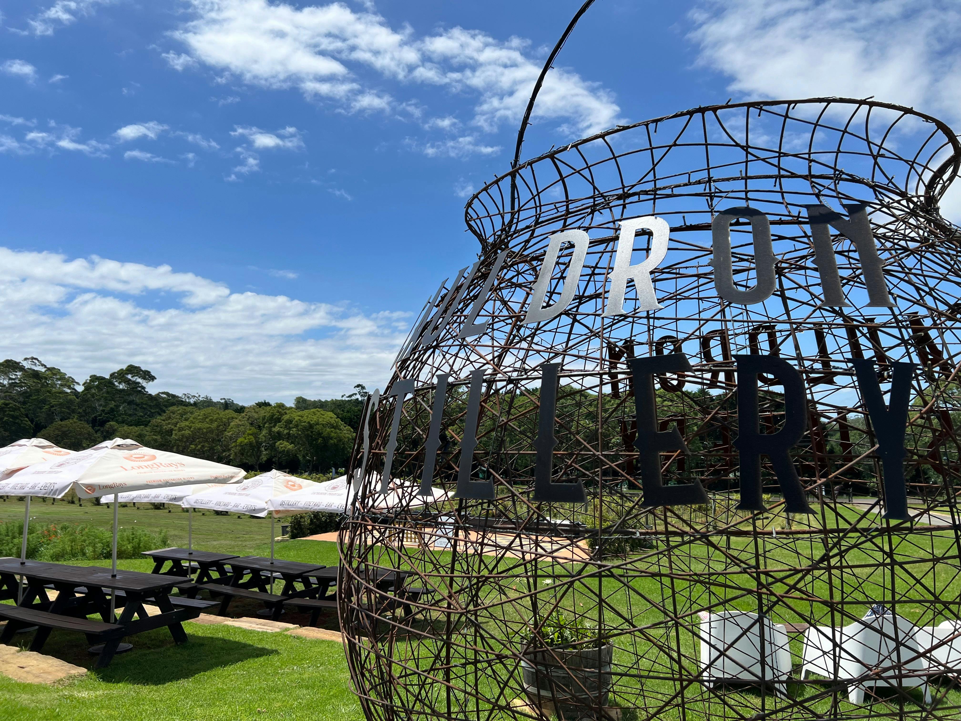 A large wire cauldron outside with Cauldron Distillery signage