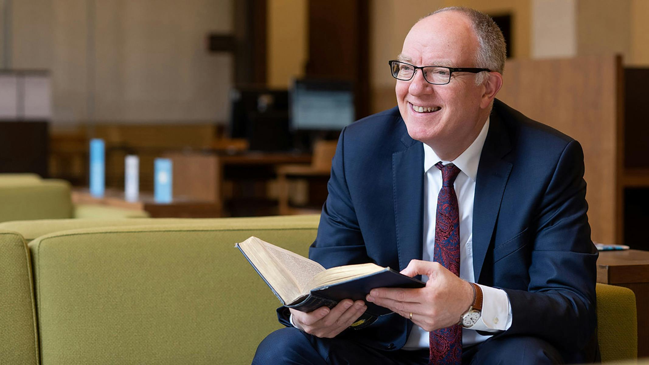 A man smiling with an open book in his hands