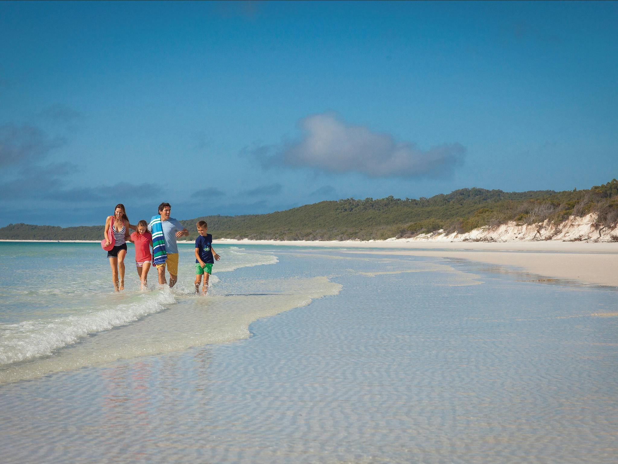 Young family on water's edge at Whitehaven Beach.