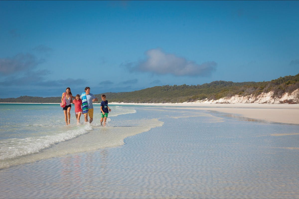 Young family on water's edge at Whitehaven Beach.