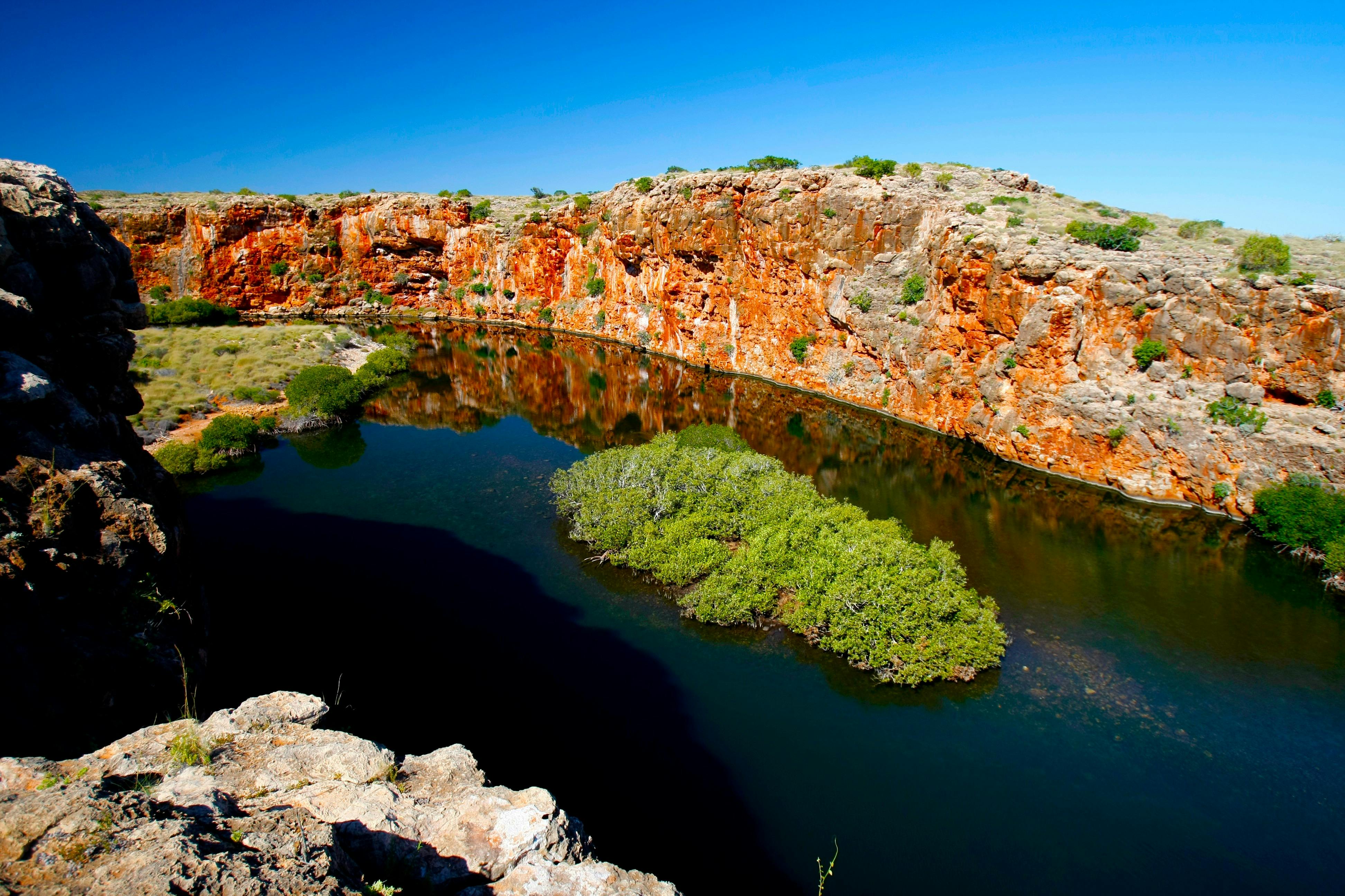 River running between a gorge of layered red rock.