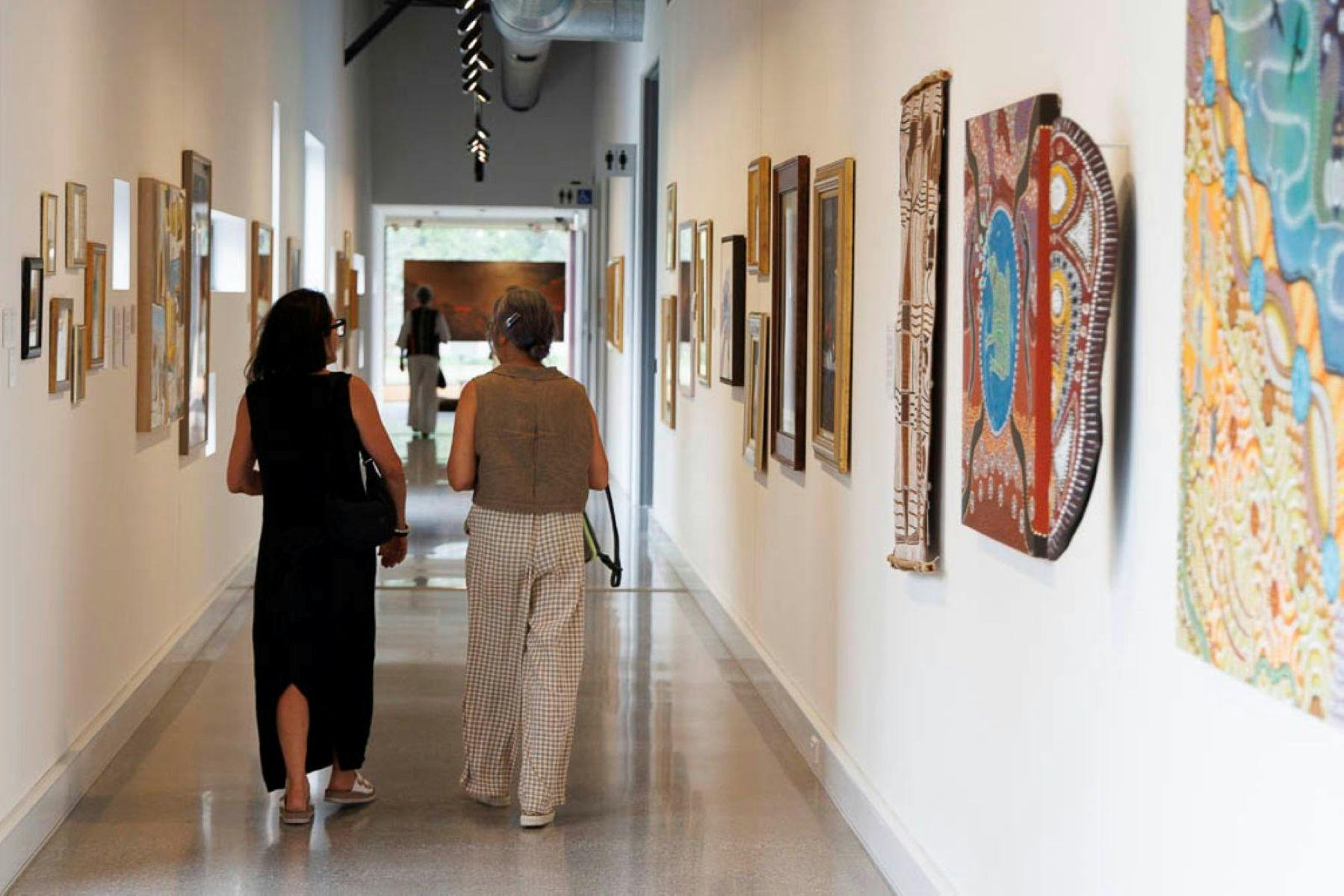 两位参观者正走过走廊展厅，这里展出了部分藏品。