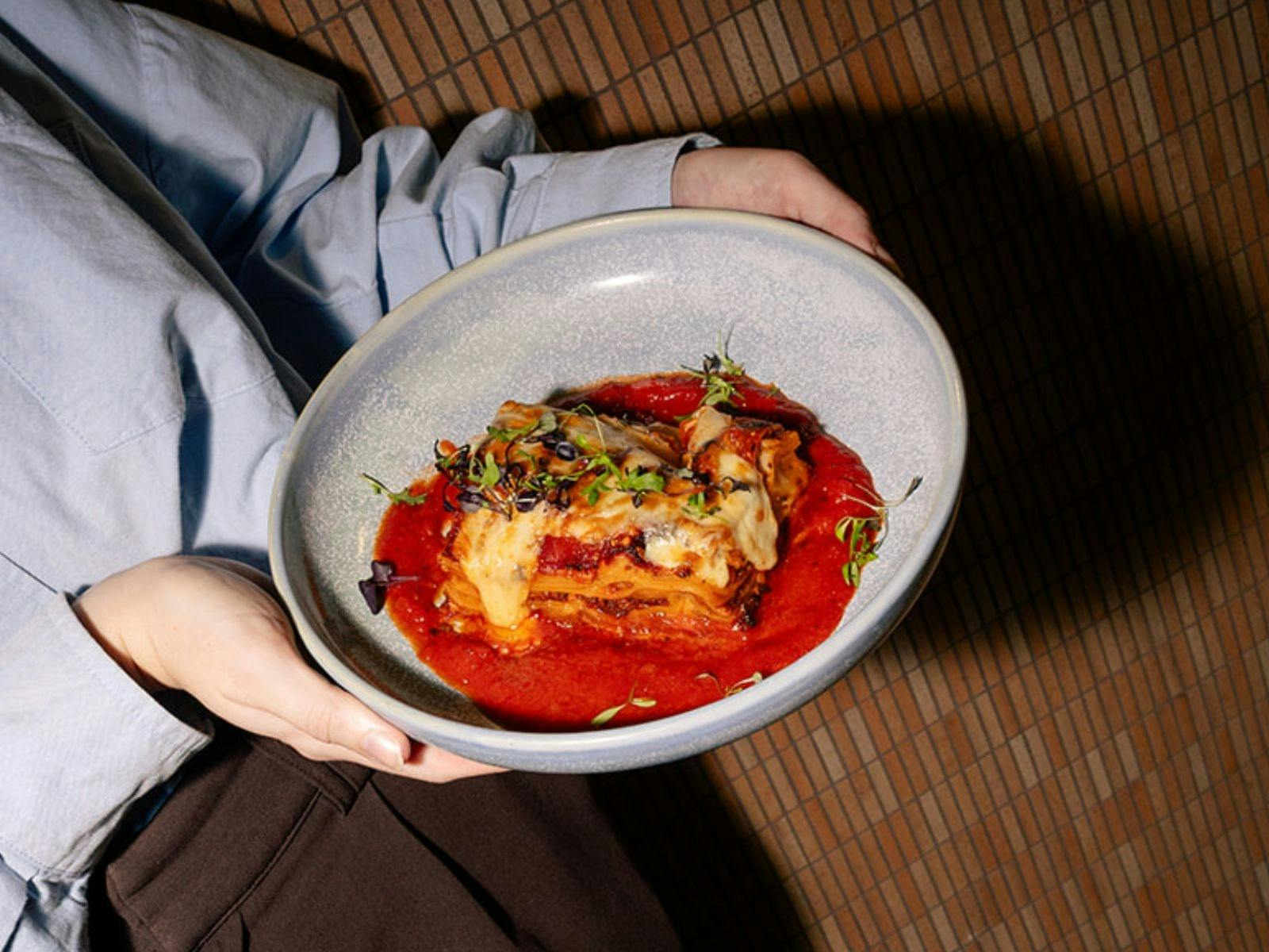 Bowl with a slice of lasagne in a red sauce