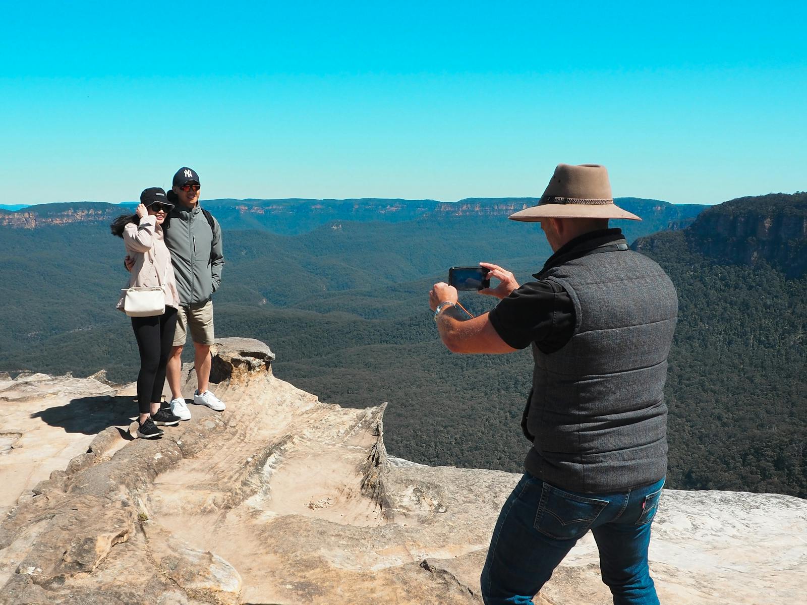 2 tourists standing at Lincol's Rock in Blue Mountains for a photo